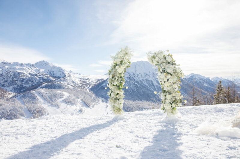 Arche fleurie positionnée dans la neige, montagnes enneigées en fond Arche fleurie positionnée dans la neige - Raja Agency