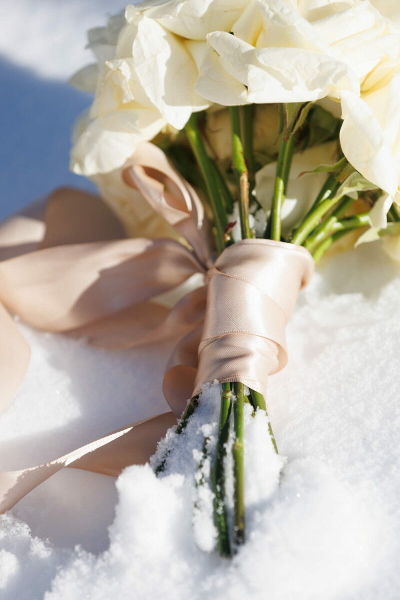 Bouquet de mariée en roses blanches, posé dans la neige Bouquet de mariée en roses blanches - Raja Agency